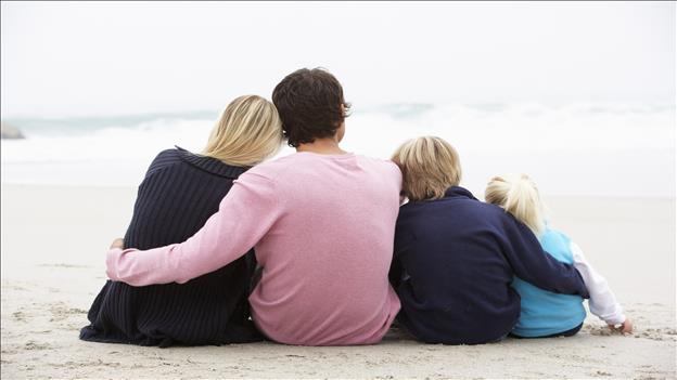 Back View of Young Family sitting on winter beach